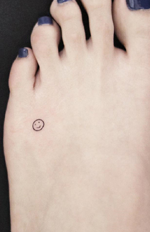 Миниатюрная тату в виде смайлика на ступне