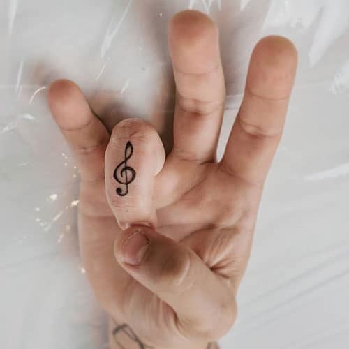 Миниатюрная тату скрипичный ключ на пальце