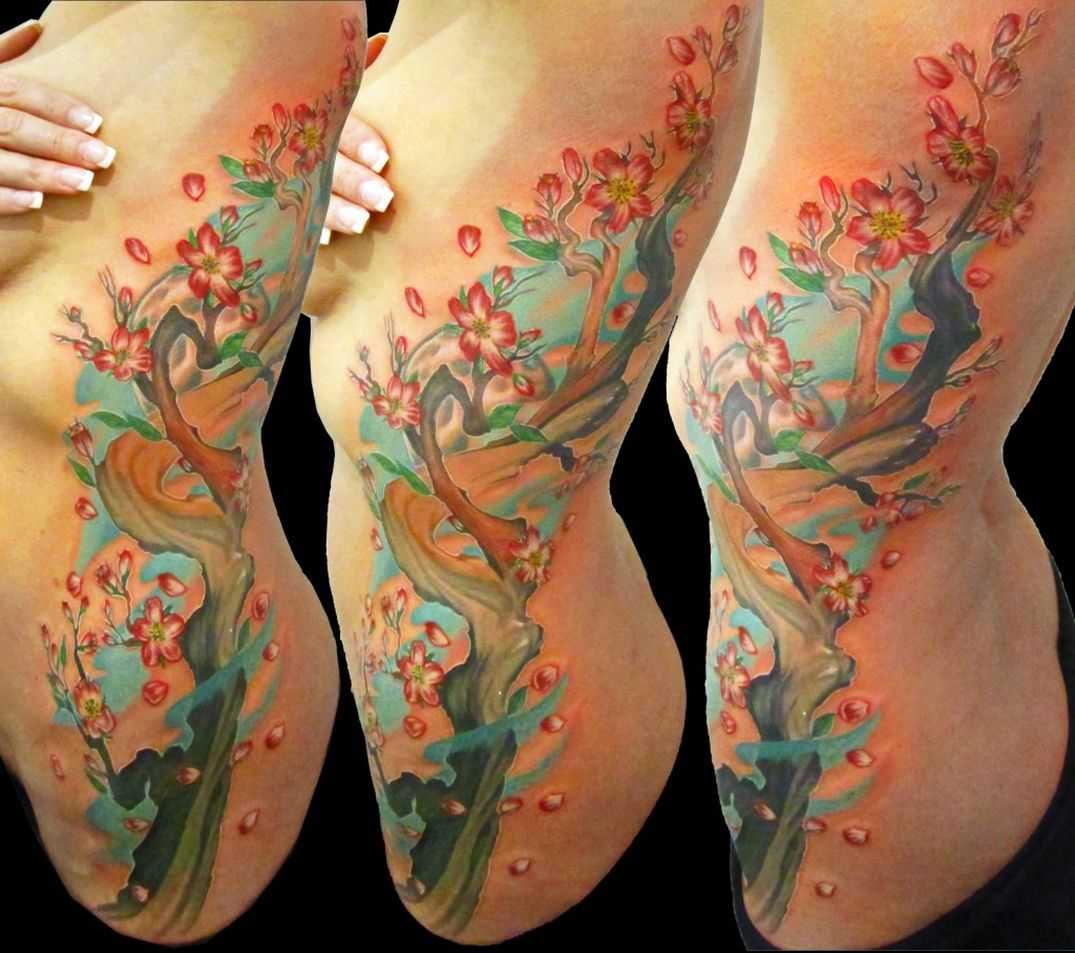 Татуировка с цветузим деревом на боку