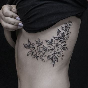 Татуировка женская графика на ребрах веточка с цветами