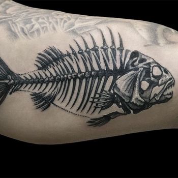 Татуировка мужская графика на бицепсе рыбий скелет