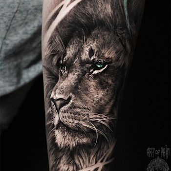 Татуировка мужская реализм на предплечье лев с зелеными глазами